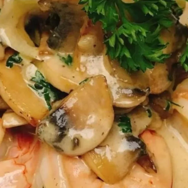 Prawn dish served with mushrooms and herbs on a white plate