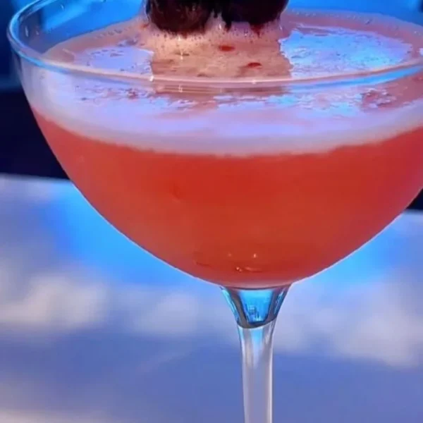 Pink cocktail served in a martini glass with cherry garnish