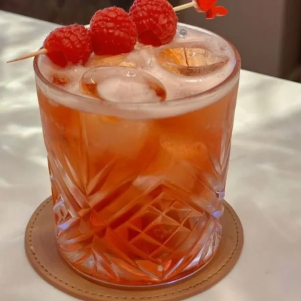 Cocktail with raspberries served over ice