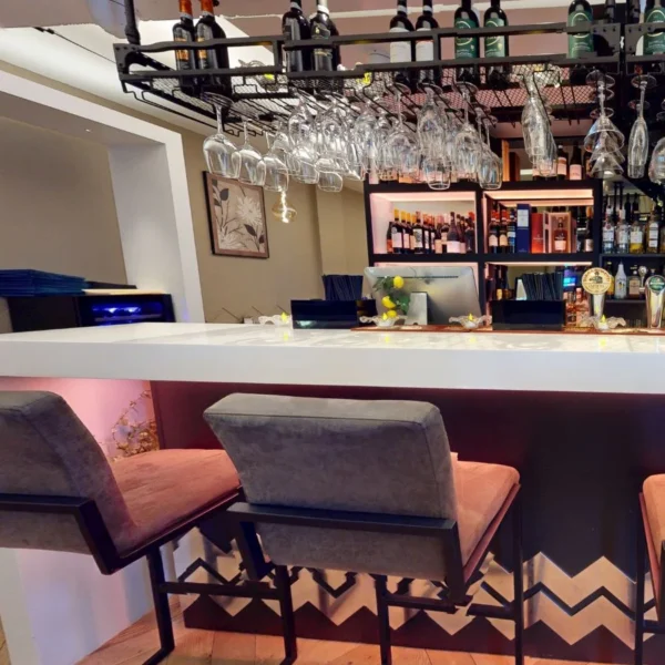 Bar seating area with wine bottles and hanging wine glasses at Bella Cucina