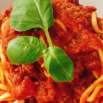 Spaghetti Bolognese with rich tomato and meat sauce topped with fresh basil