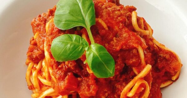 Spaghetti Bolognese with rich tomato and meat sauce topped with fresh basil